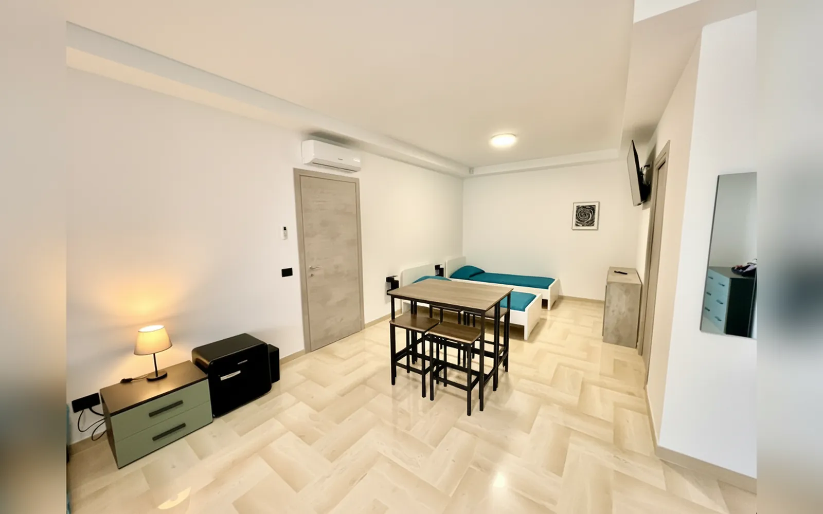 Il tavolo alto e il letto nella camera familiare, con la porta d’ingresso